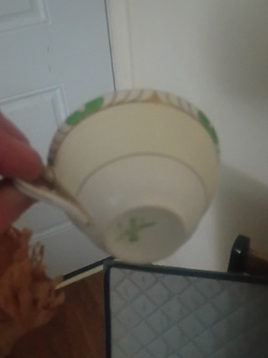 Porcelain teacup and saucer with green trim and gold accents