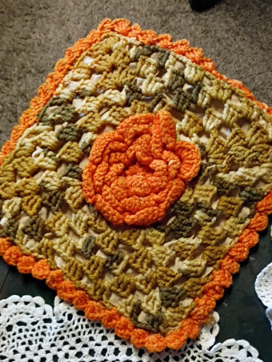 Handmade crocheted granny square doily or potholder in orange and olive green yarn