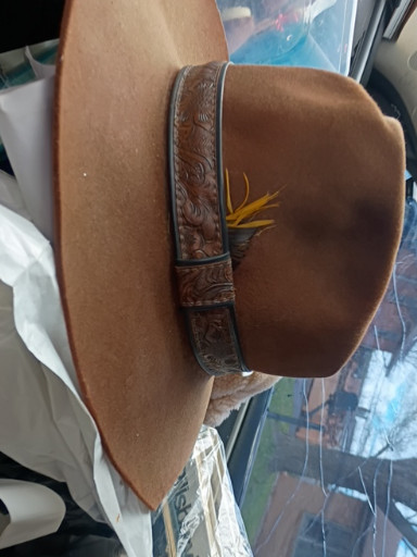 Brown felt cowboy hat with hand-tooled leather band and feather decoration