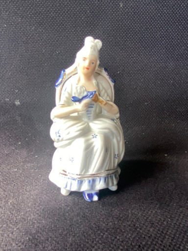 Porseleinen beeldje van een zittende dame in barokke stijl met blauw-wit decoratie