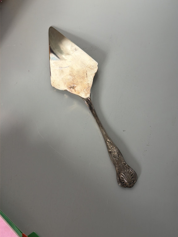 Silver-plated cake or pie server with decorative shell and scroll pattern handle