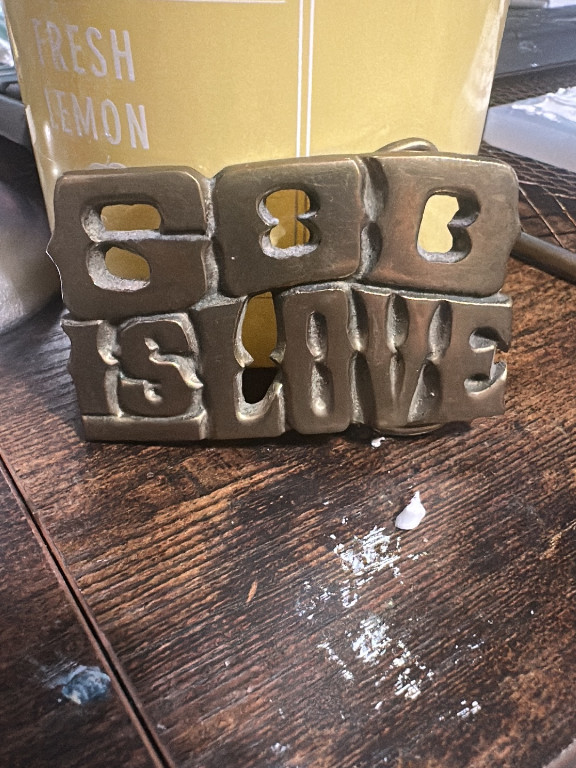 Metal belt buckle spelling 'GOD IS LOVE'