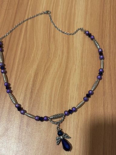 Costume jewelry necklace with purple beads and angel wing pendant