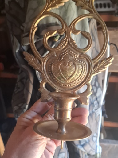 Bronze candlestick with ornate scrollwork and heart-shaped decorative motif
