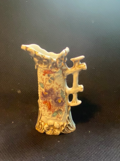 Porselein kan met bloemmotief en decoratieve handvatten