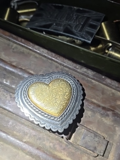 Silver and gold-tone metal belt buckle with engraved double heart design