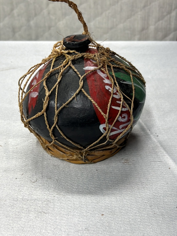 Black clay mezcal bottle with hand-painted decoration and jute netting from Oaxaca, Mexico