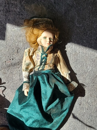 Porcelain doll in Victorian-style green dress and hat