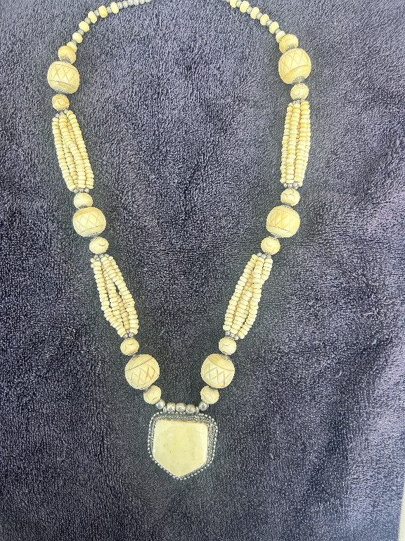 Vintage hand-carved bone or celluloid necklace with shield pendant and peacock motifs