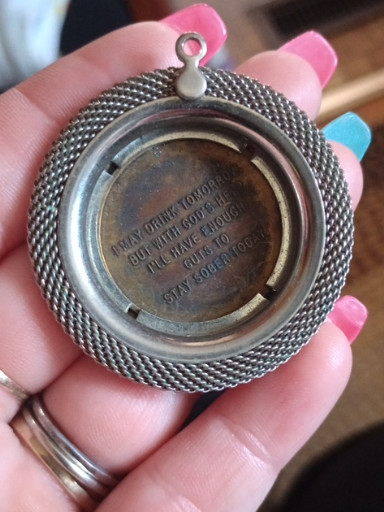 Silver-toned metal pendant with engraved inscription, likely a watch fob or locket frame