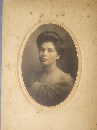 Vintage sepia-toned studio portrait photograph of a young woman, circa early 1900s