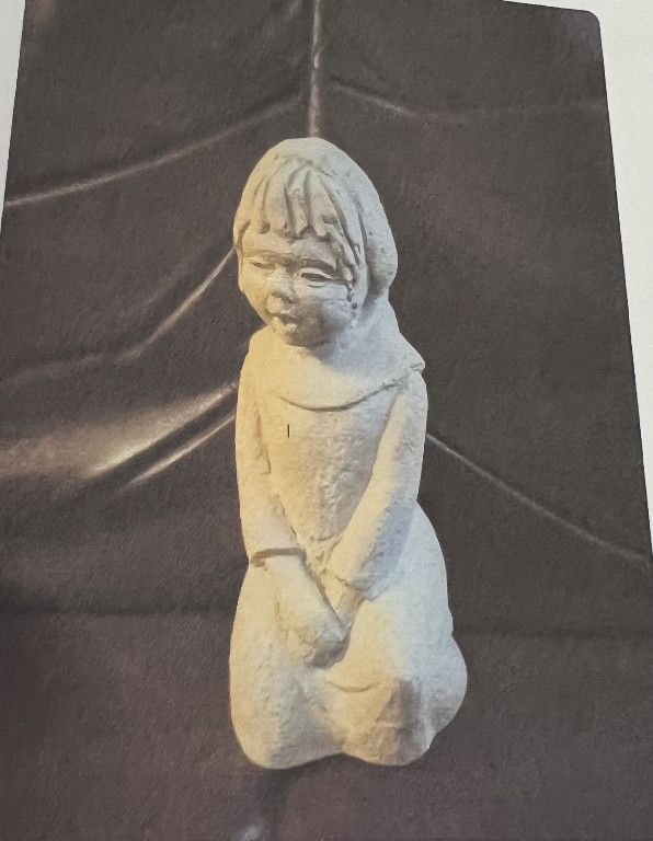 Concrete sculpture of a kneeling child figure by Andro