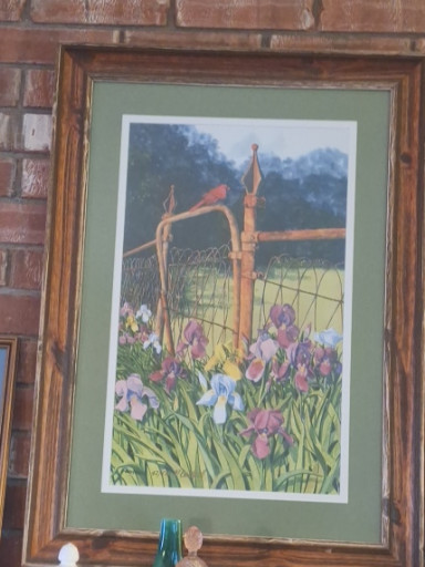 Framed print of a watercolor painting titled 'Pansies and Cardinal' featuring a garden scene with irises, pansies, and a cardinal perched on a wooden fence