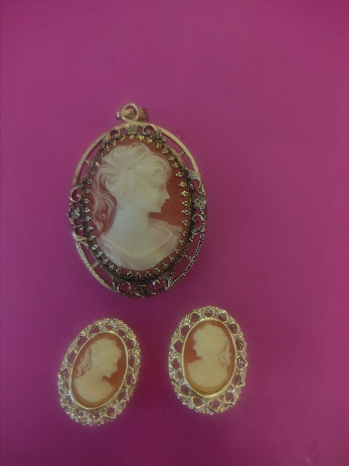 Vintage cameo jewelry set consisting of one pendant and two matching earrings with ornate gold-tone frames