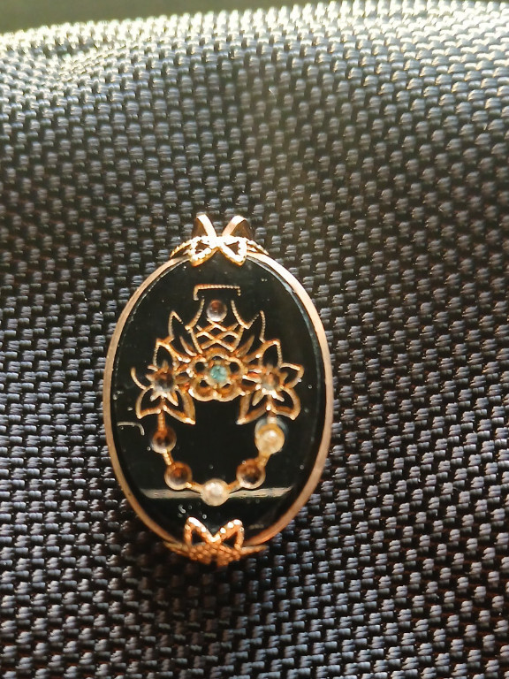 Gold-plated pendant with floral basket design on black enamel background