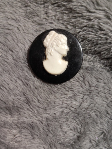 Vintage molded plastic cameo brooch with white profile on black background