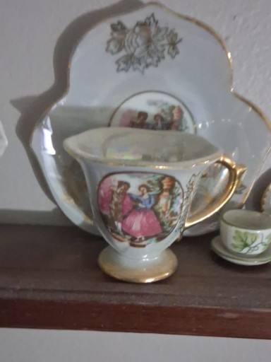 Porcelain demitasse cup and saucer with Victorian courting scene and gold trim
