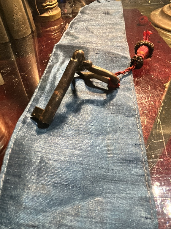 Chiave antica in ottone con decorazione a sfera e cordino rosso