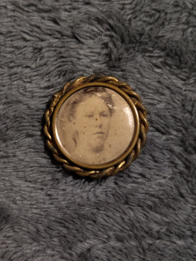 Victorian-era mourning brooch with sepia photograph in gold-tone metal frame