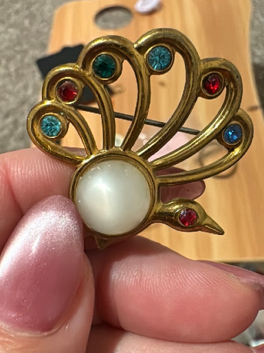 Gold-tone metal brooch with multicolored rhinestones and faux pearl center in peacock or fan motif