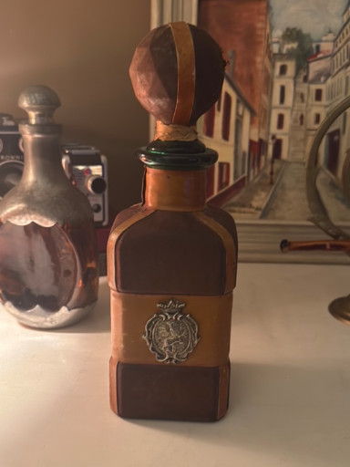 Vintage leather-wrapped glass decanter with ornate metal medallion