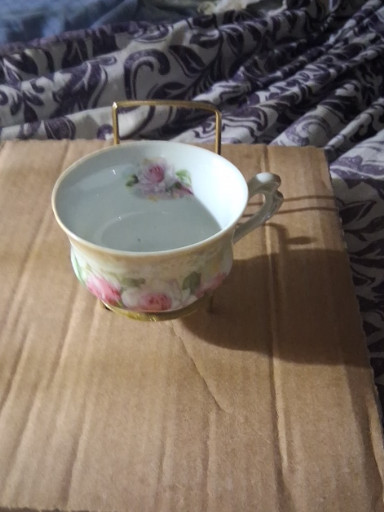 Porcelain teacup with floral decoration and brass wire handle