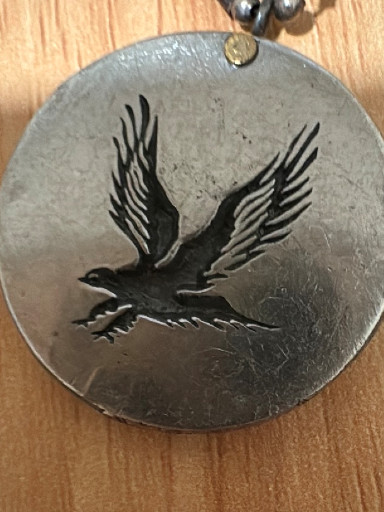 Pewter or silver-toned metal pendant featuring an eagle in flight design