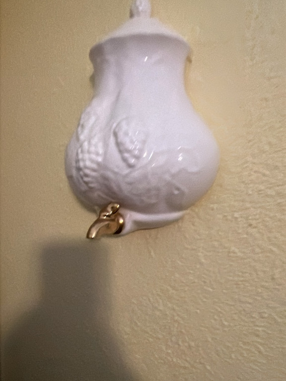 White ceramic wall pocket planter with embossed grape vine design and brass spout