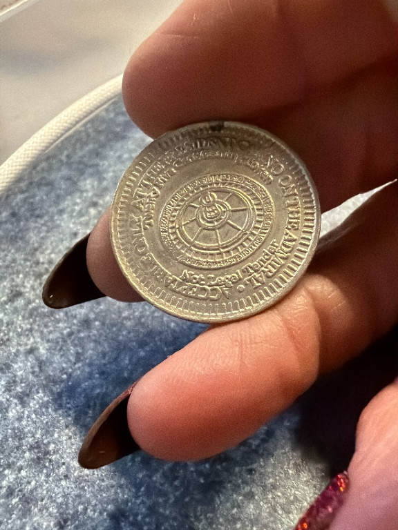 Silver-colored commemorative token or medal with Arabic inscriptions and geometric design