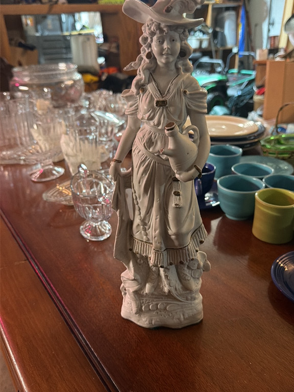 Bisque porcelain figurine depicting a woman in period dress with a water jug