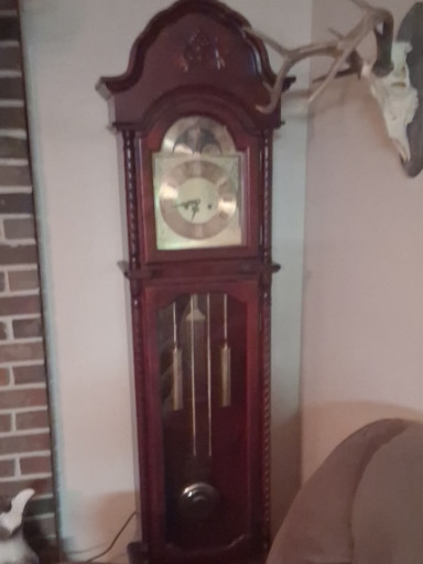 Wooden grandfather clock with ornate bonnet pediment and brass weights