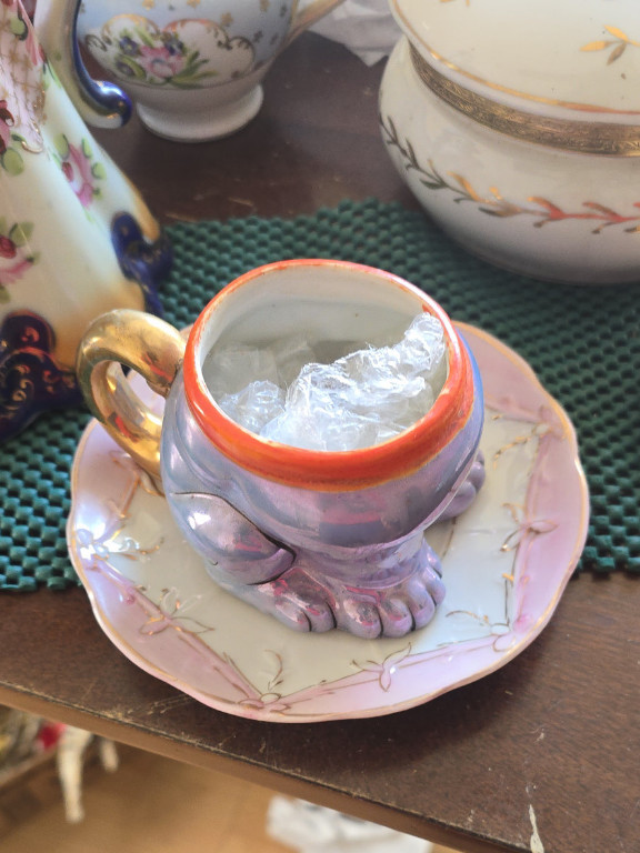 Ceramic novelty cup shaped as feet with gold handle and matching floral saucer, 'Bonzo Dog' lusterware series