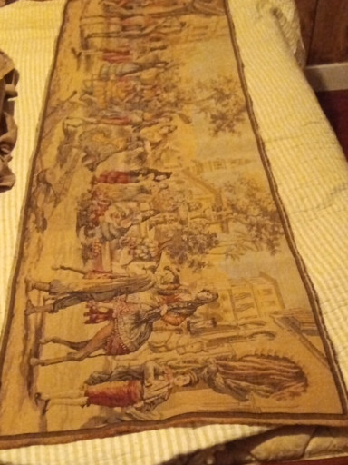 Antique tapestry wall hanging depicting pastoral or courtly scenes in warm golden-brown tones