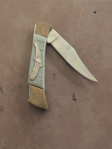 Folding pocket knife with brass handle featuring eagle and American flag motif