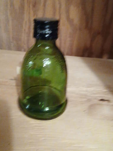 Green glass miniature wine bottle with black cap by Wine World, 1976