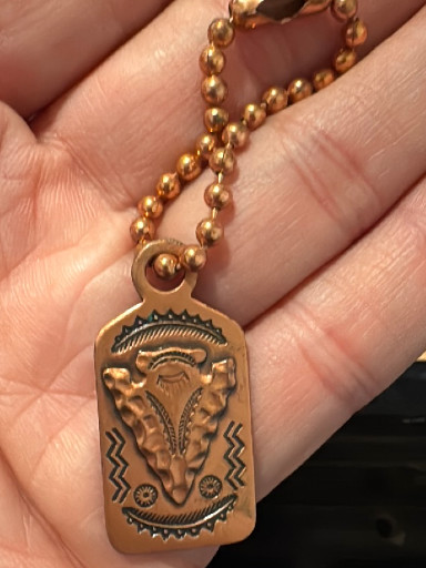 Copper dog tag pendant with stamped Native American Navajo design featuring thunderbird and geometric motifs