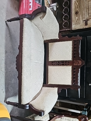 Carved wood settee with upholstered seat and back, featuring decorative carved details and turned legs