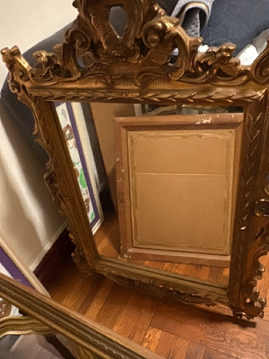 Ornate gilded wood Baroque-style wall mirror with elaborate scrollwork and foliate crest