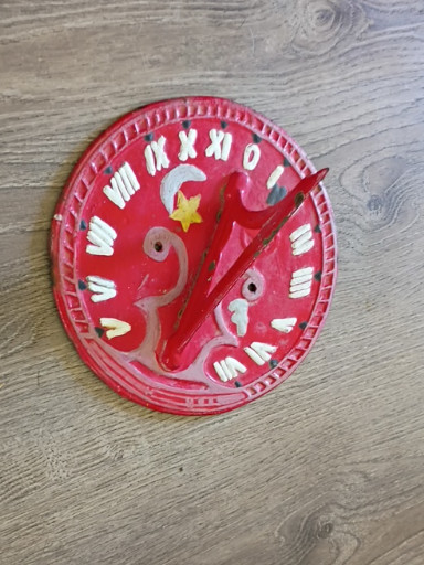 Metal sundial with painted red finish and decorative bird motif from the 1950s