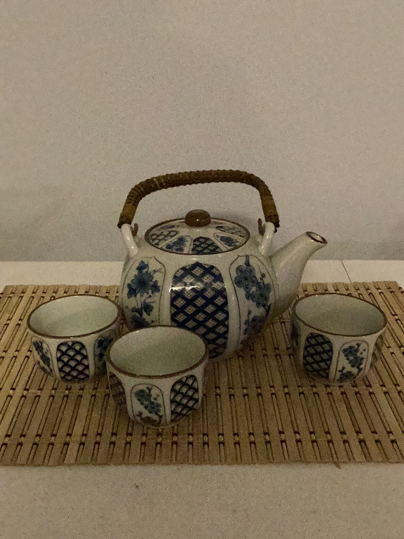 Porcelain tea set with teapot and three cups, featuring blue and white floral and lattice pattern with wicker handle, Japanese style