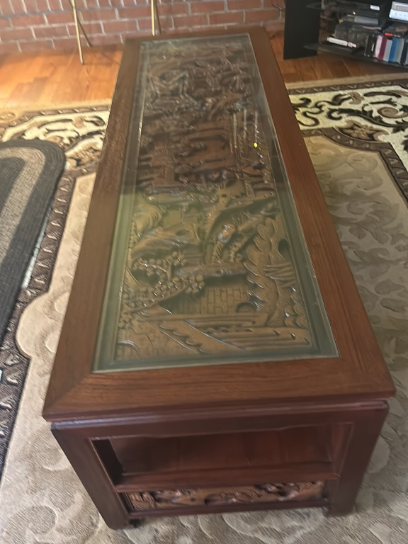 Carved wooden coffee table with glass top featuring Chinese scenic relief design