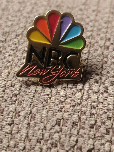 Metal enamel lapel pin featuring NBC New York peacock logo