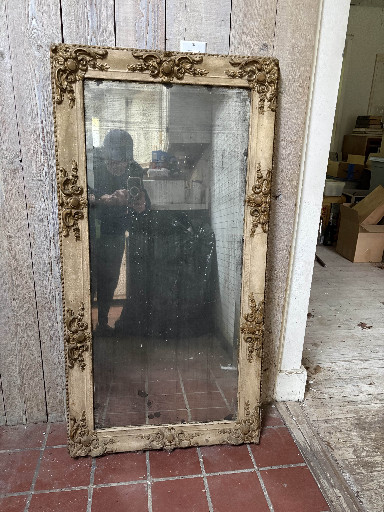 Large beveled glass mirror with ornate carved wood frame in distressed cream finish with gilded floral motifs