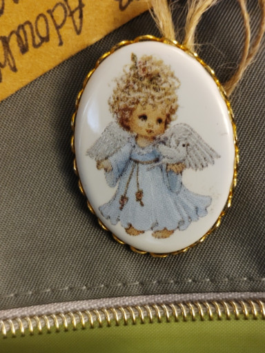 Porcelain cameo brooch featuring a child angel with wings in a blue dress