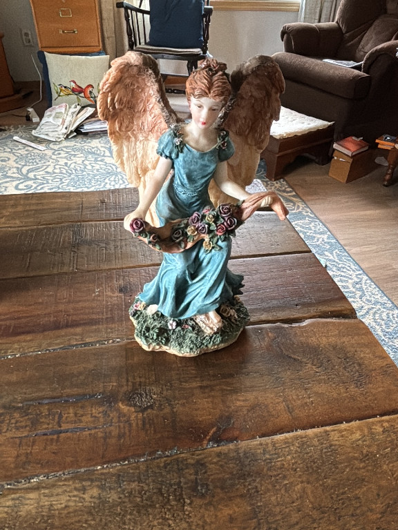 Resin angel figurine holding a basket of roses
