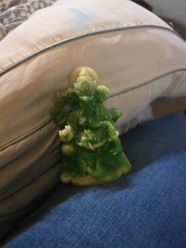 Carved jade or jadeite figurine depicting Budai (Laughing Buddha) holding a sack and coins