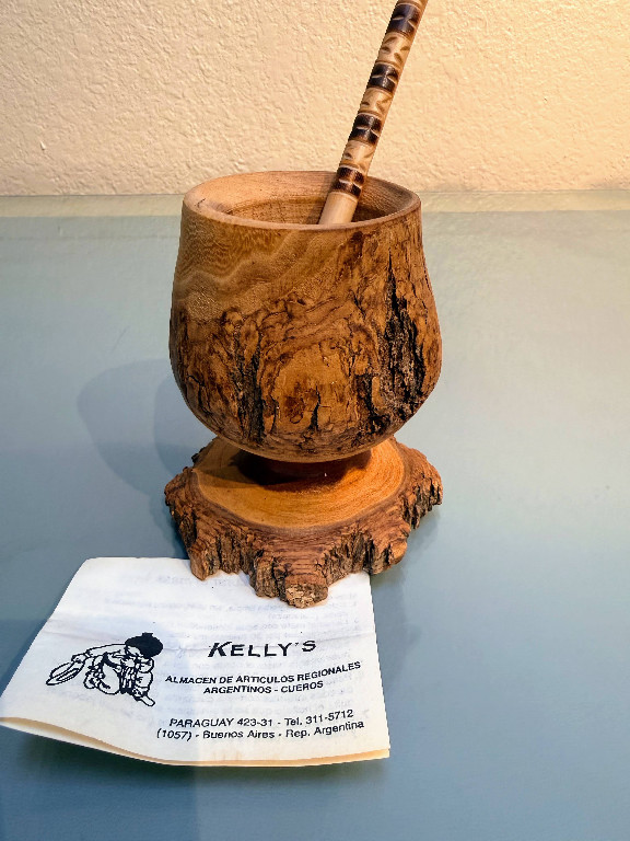 Hand-turned wood mortar and pestle with live-edge bark detail on natural wood base