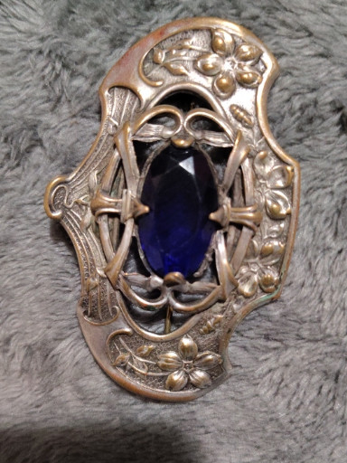 Art Deco style brooch with cobalt blue glass center stone and ornate openwork metal frame