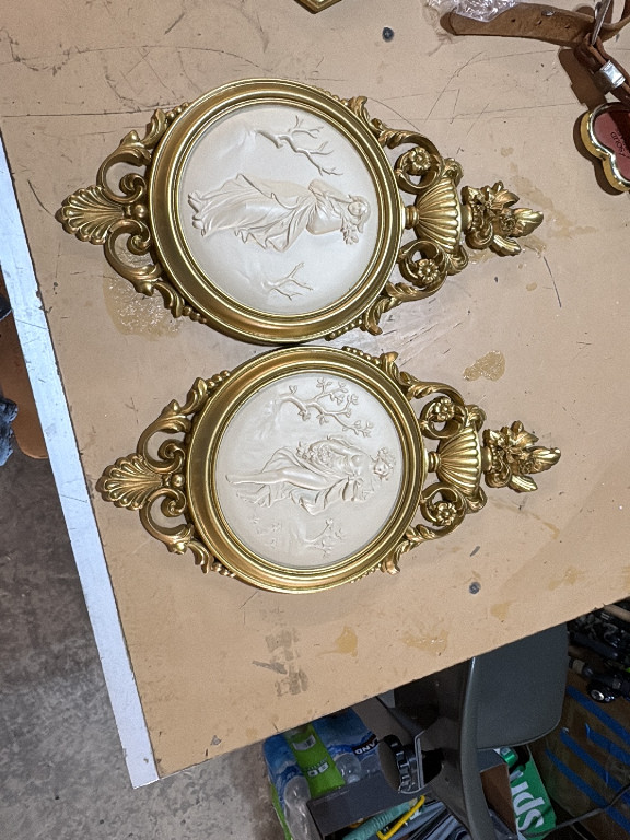 Pair of decorative wall plaques with molded relief depicting classical female figures in ornate gilt frames