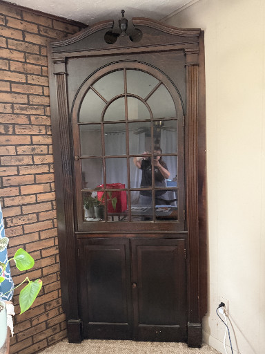 Mahogany corner cabinet with glazed upper door and carved pediment